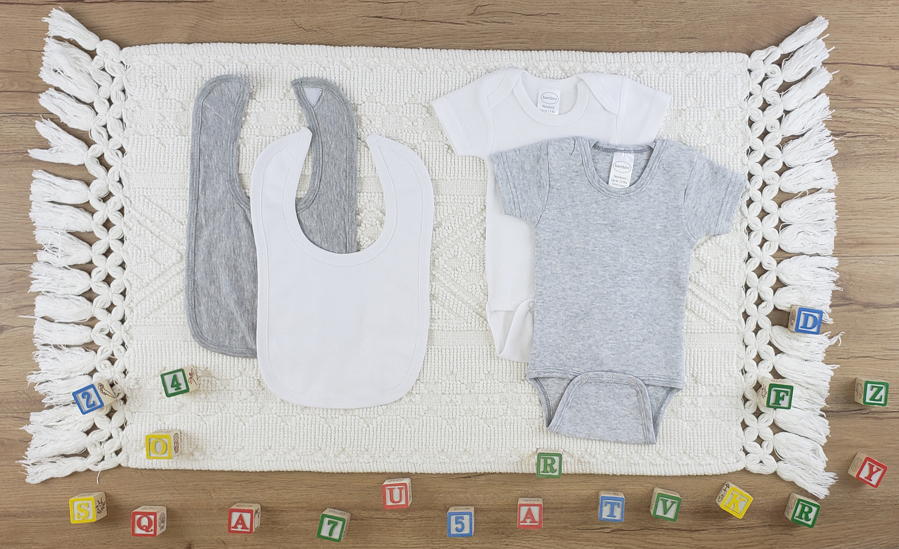 Bambini 4 Pc Layette Baby Clothes Set featuring soft cotton bibs and onesies in white and grey, perfect for newborn comfort.