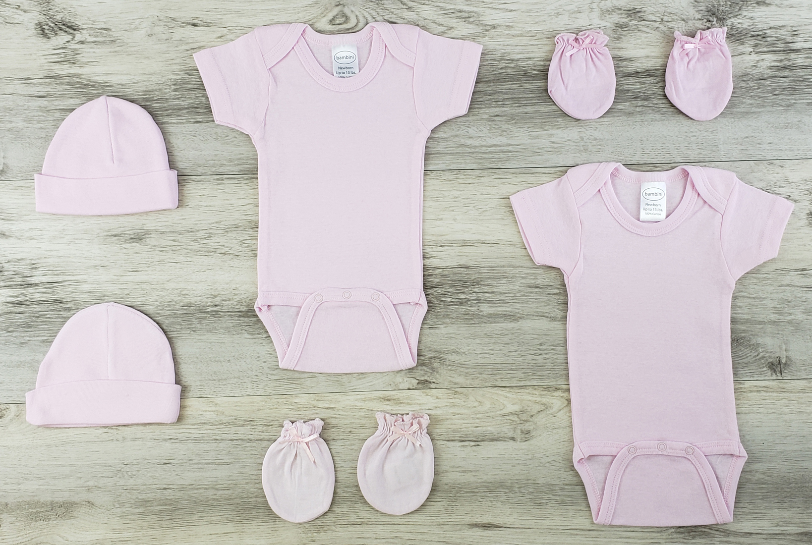 Bambini 6 Pc Layette Baby Clothes Set featuring pink short sleeve onesies, baby caps, and infant mittens made from soft cotton.