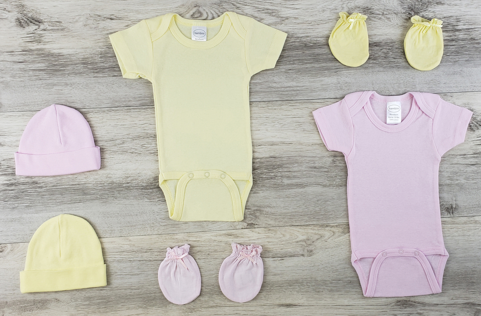 Bambini 7 Pc Layette Baby Clothes Set featuring pink and yellow onesies, baby caps, and mittens made from soft cotton.