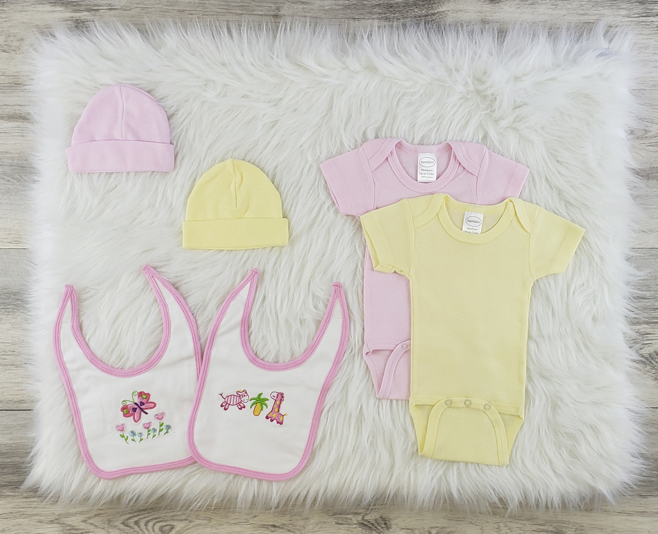 Bambini 7 Pc Layette Baby Clothes Set featuring soft cotton onesies, baby caps, and bibs in pastel colors, perfect for newborns.