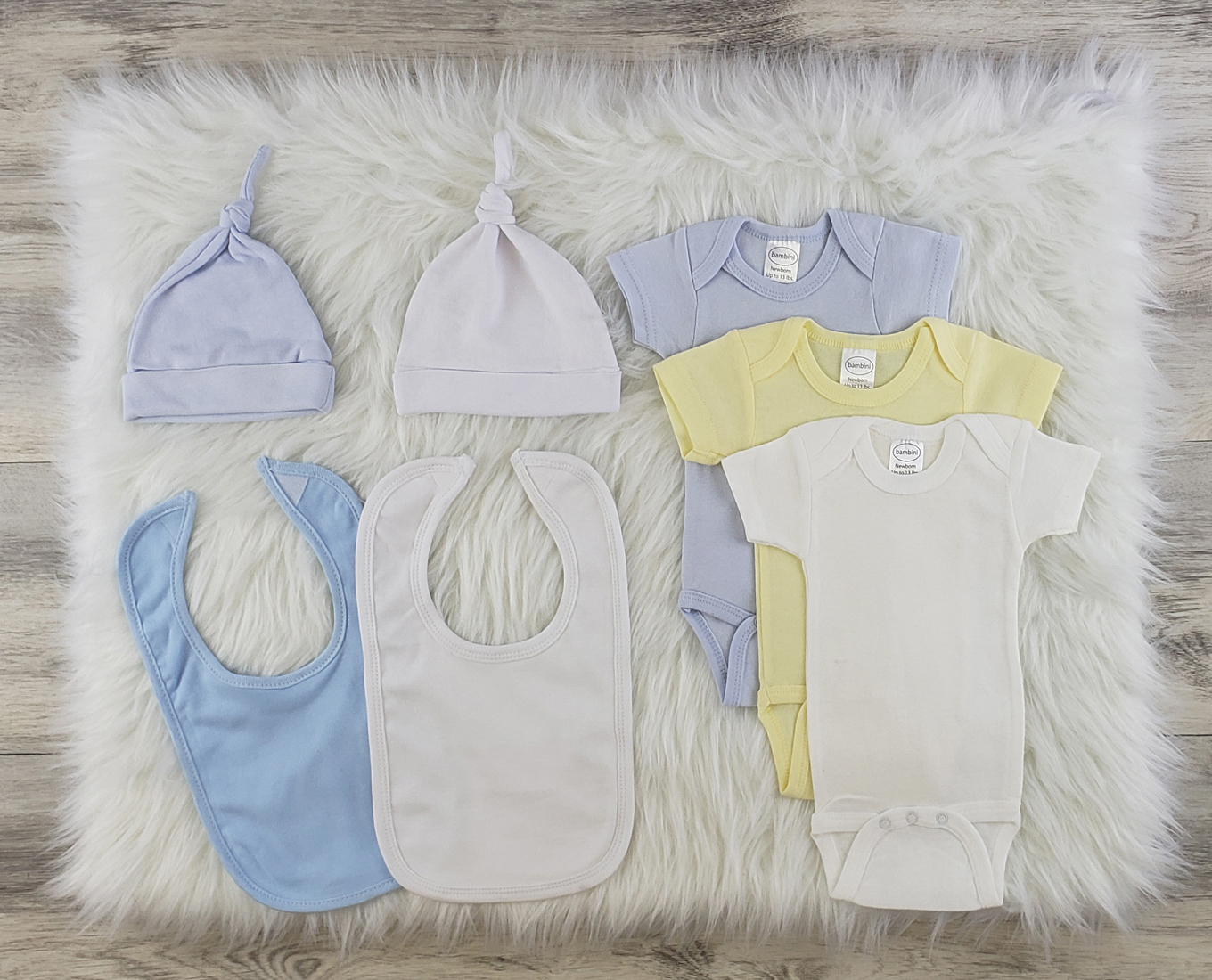 Bambini 7 Pc Layette Baby Clothes Set featuring soft cotton onesies, knotted caps, and bibs in blue and yellow colors.