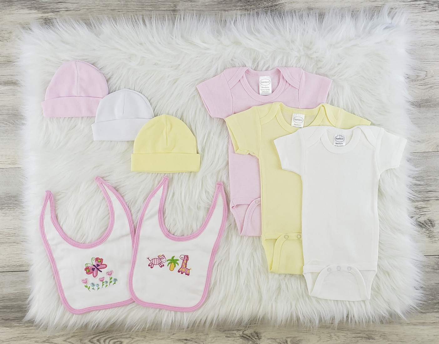 Bambini 8 Pc Layette Baby Clothes Set featuring soft cotton onesies, baby caps, and bibs in pink, yellow, and white.