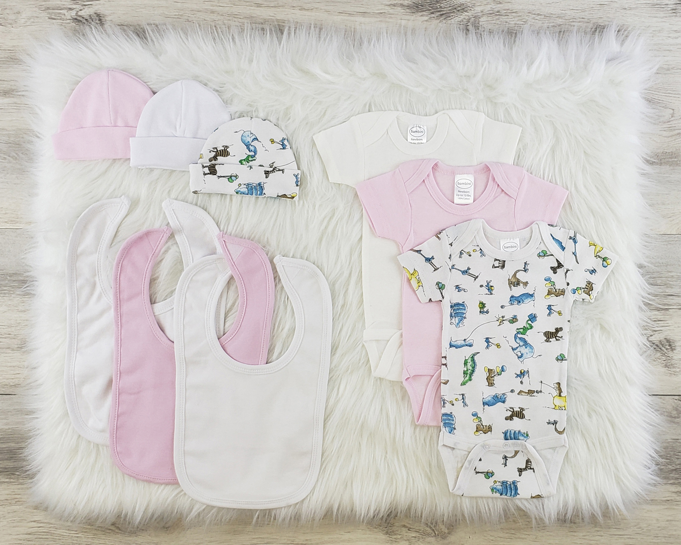 Bambini 9 Pc Layette Baby Clothes Set featuring soft cotton onesies, baby caps, and bibs in pink and white colors.