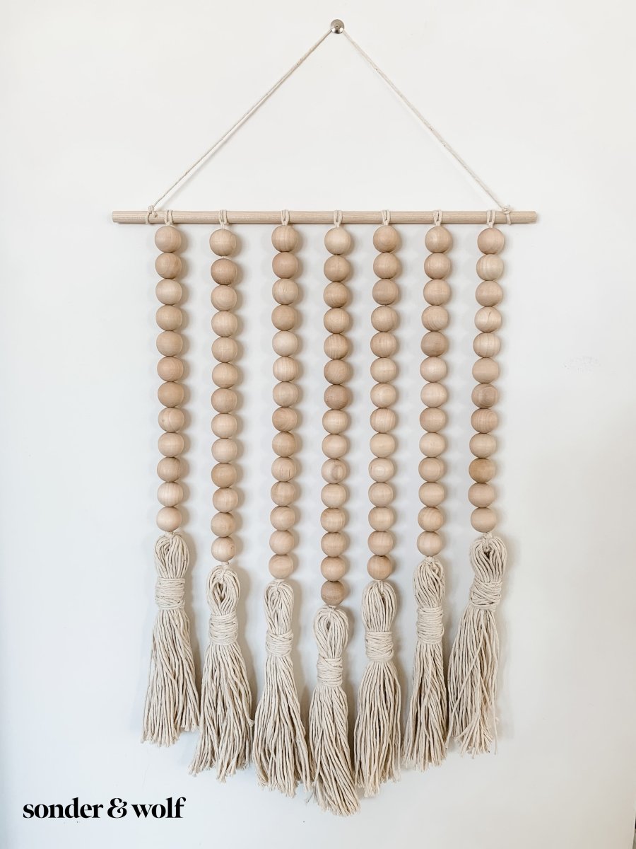 Beaded Wall Art featuring wooden beads and cotton tassels, showcasing a boho-inspired design perfect for home decor.