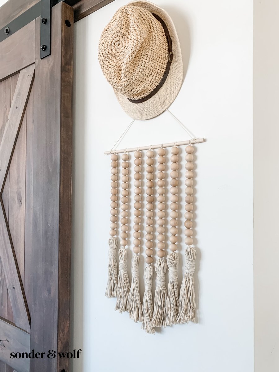 Beaded Wall Art featuring wooden beads and cotton tassels, showcasing a boho-inspired design perfect for home decor.