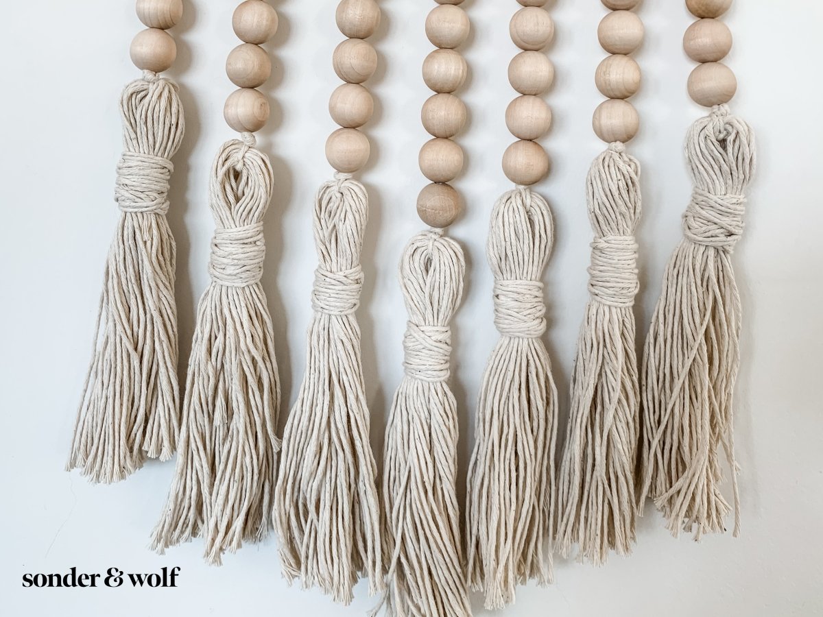 Beaded Wall Art featuring wooden beads and cotton tassels, showcasing a boho-inspired design perfect for home decor.