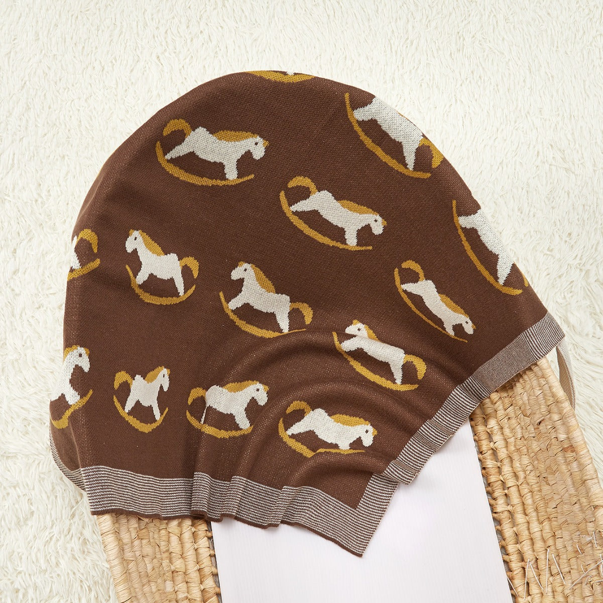 A cozy knitted baby blanket featuring a charming horse pattern in blue and coffee colors, perfect for children of all ages.