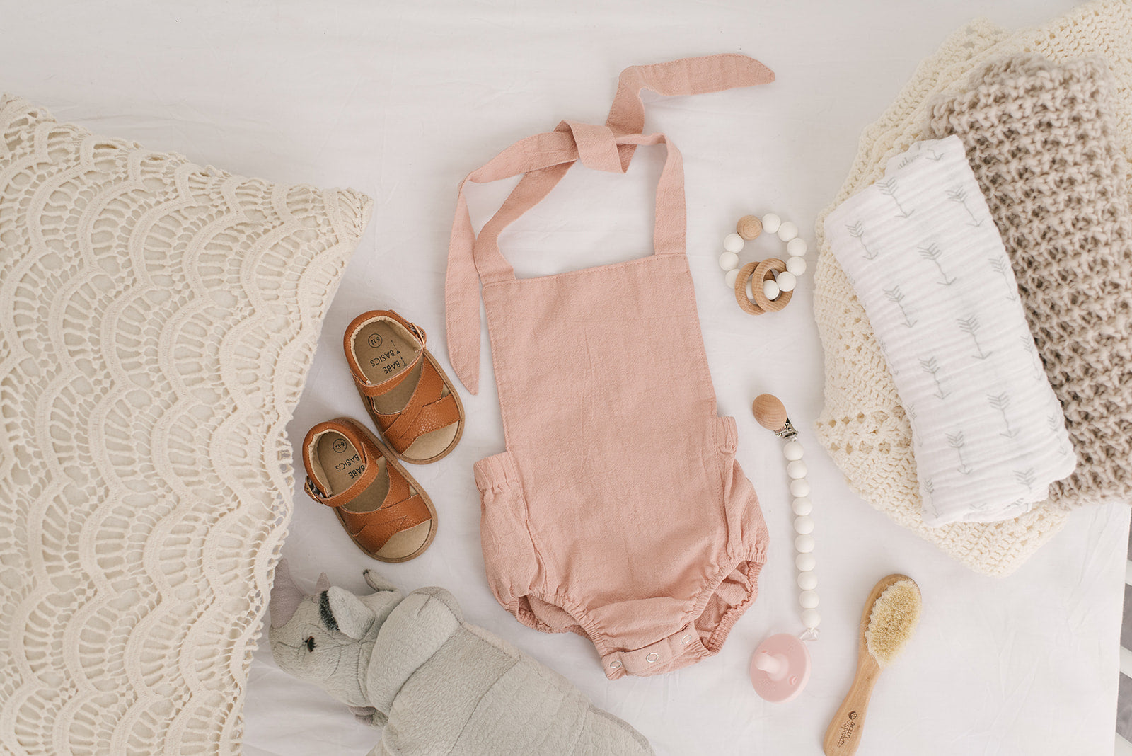 A stylish blush halter romper for babies, made from soft linen with diaper snaps.