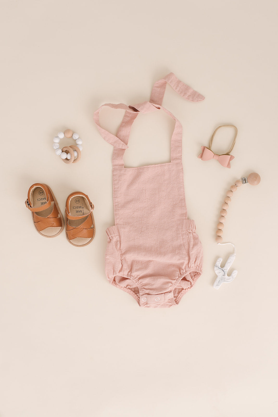 A stylish blush halter romper for babies, made from soft linen with diaper snaps.