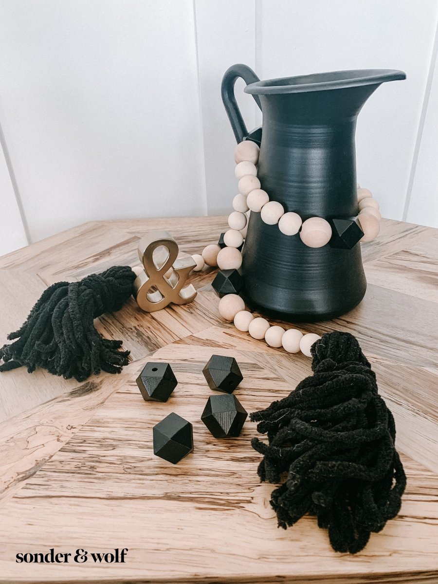 A beautifully handcrafted Boho Wood Bead Garland featuring light unfinished wood beads and stylish black tassels, perfect for home decor.