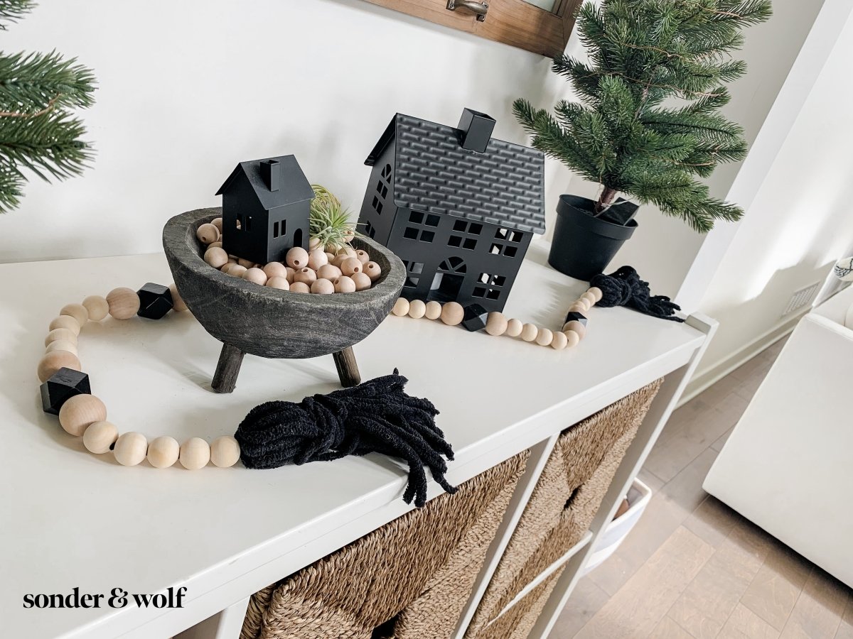 A beautifully handcrafted Boho Wood Bead Garland featuring light unfinished wood beads and stylish black tassels, perfect for home decor.