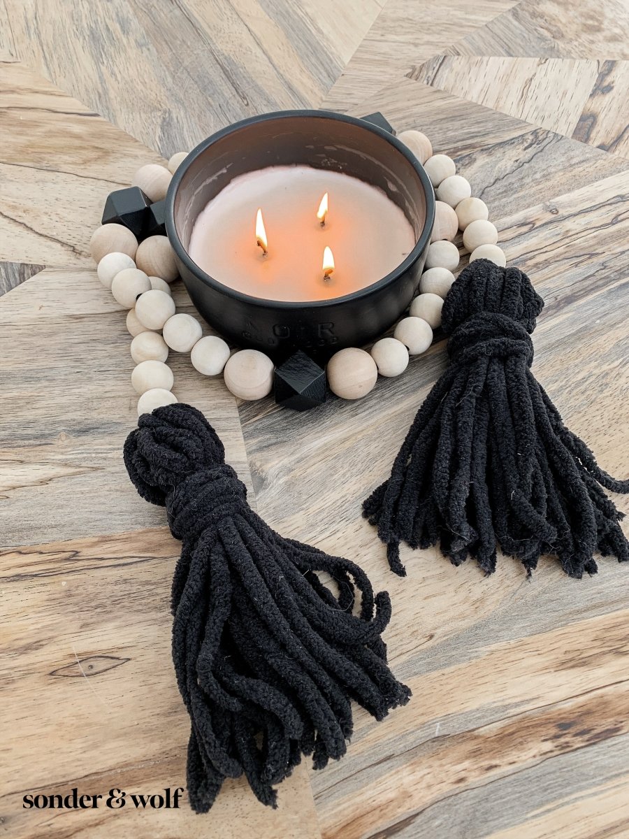 A beautifully handcrafted Boho Wood Bead Garland featuring light unfinished wood beads and stylish black tassels, perfect for home decor.