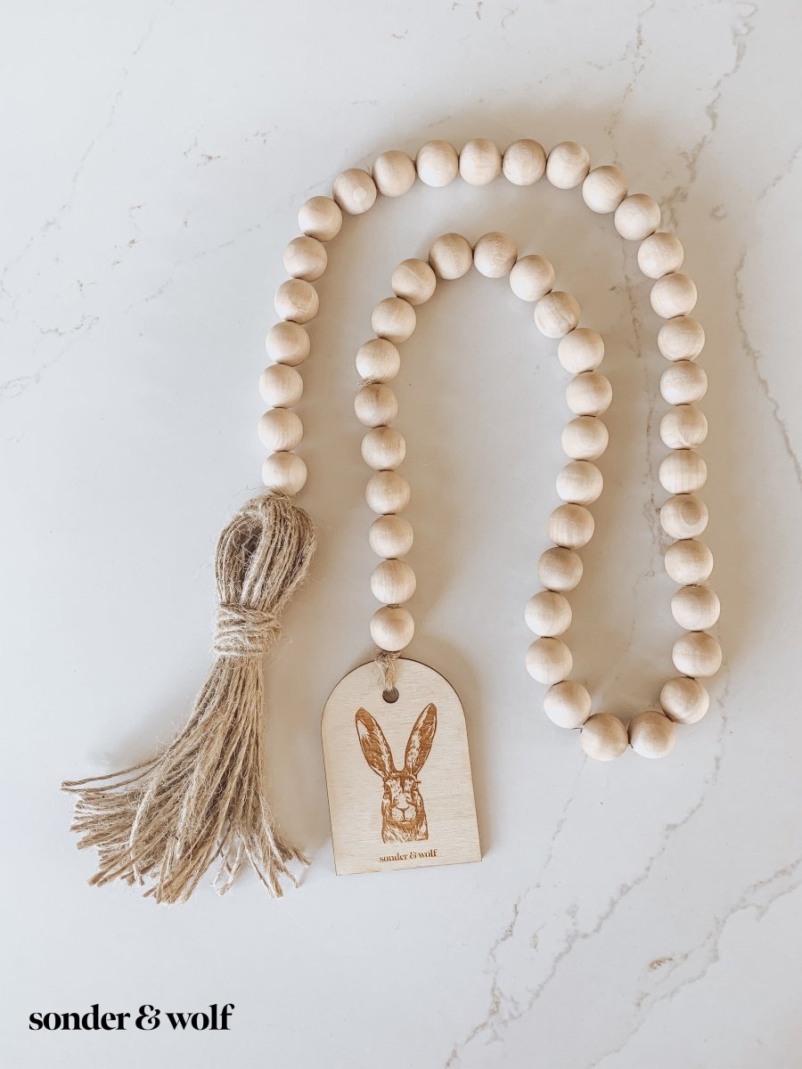 Bunny Wood Bead Garland featuring light wood beads and a jute tassel, perfect for home decor.