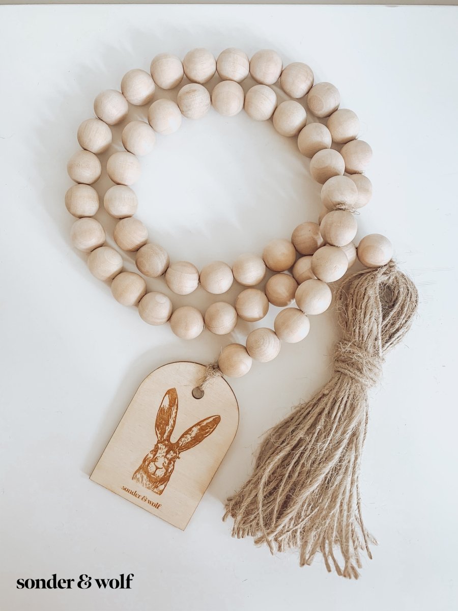 Bunny Wood Bead Garland featuring light wood beads and a jute tassel, perfect for home decor.