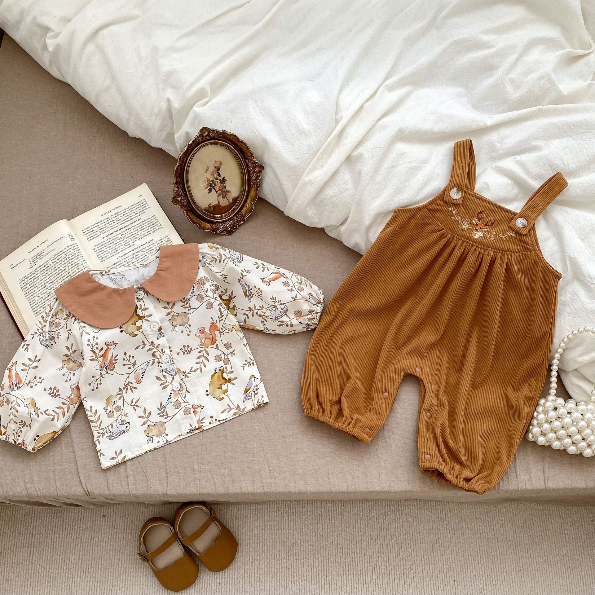 A cute baby girl wearing a Cartoon Graphic Autumn Romper in white with floral patterns, perfect for autumn fashion.