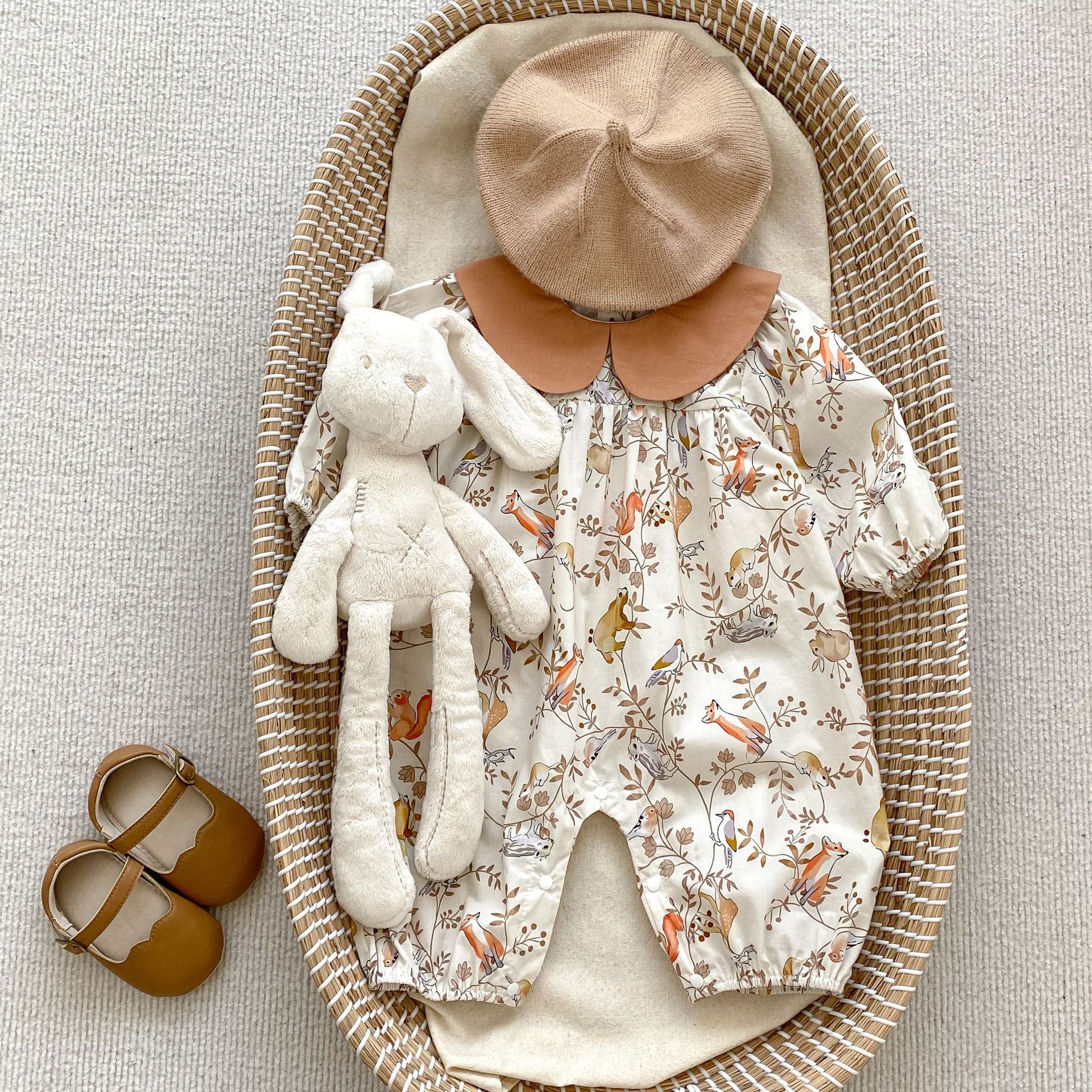 A cute baby girl wearing a Cartoon Graphic Autumn Romper in white with floral patterns, perfect for autumn fashion.