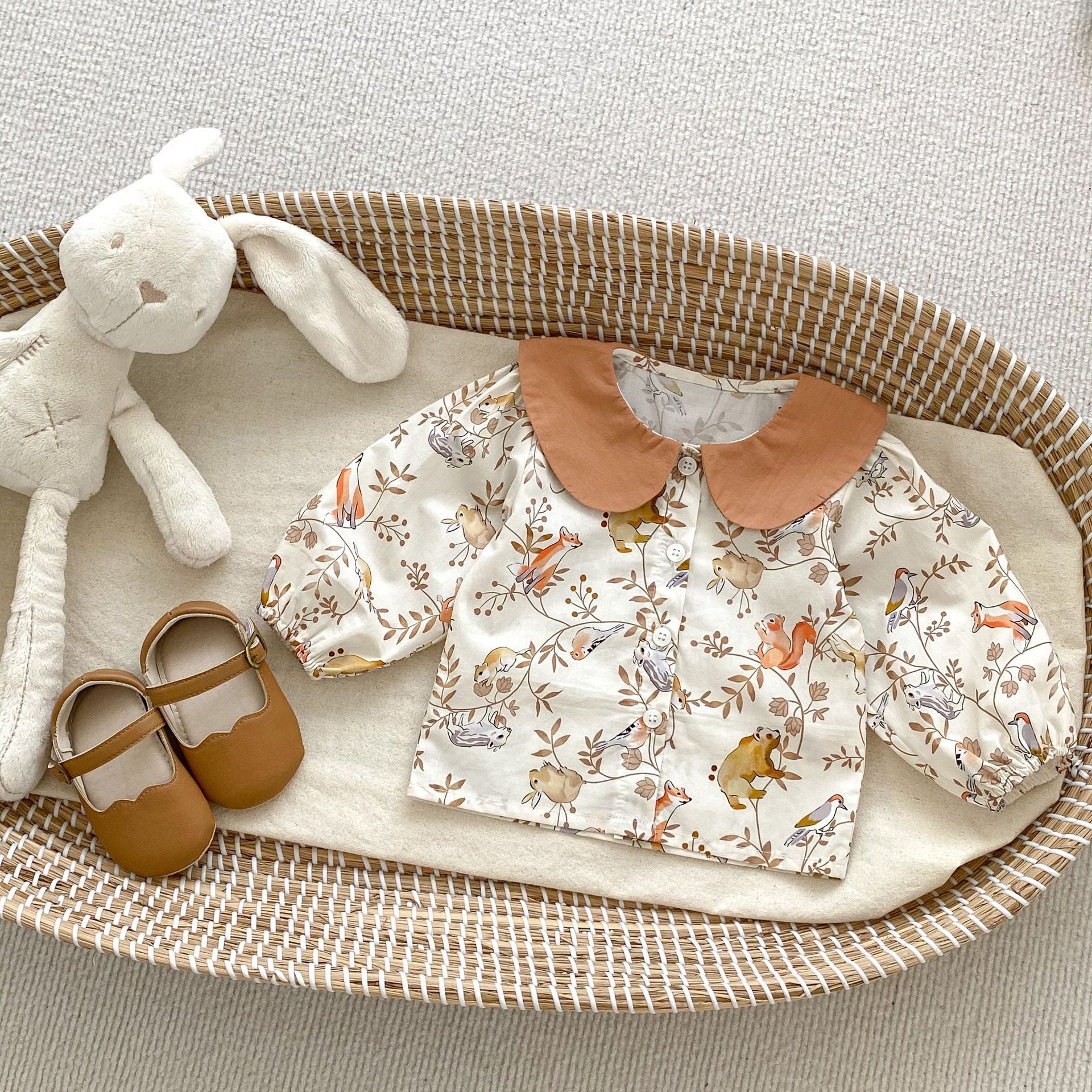 A cute baby girl wearing a Cartoon Graphic Autumn Romper in white with floral patterns, perfect for autumn fashion.