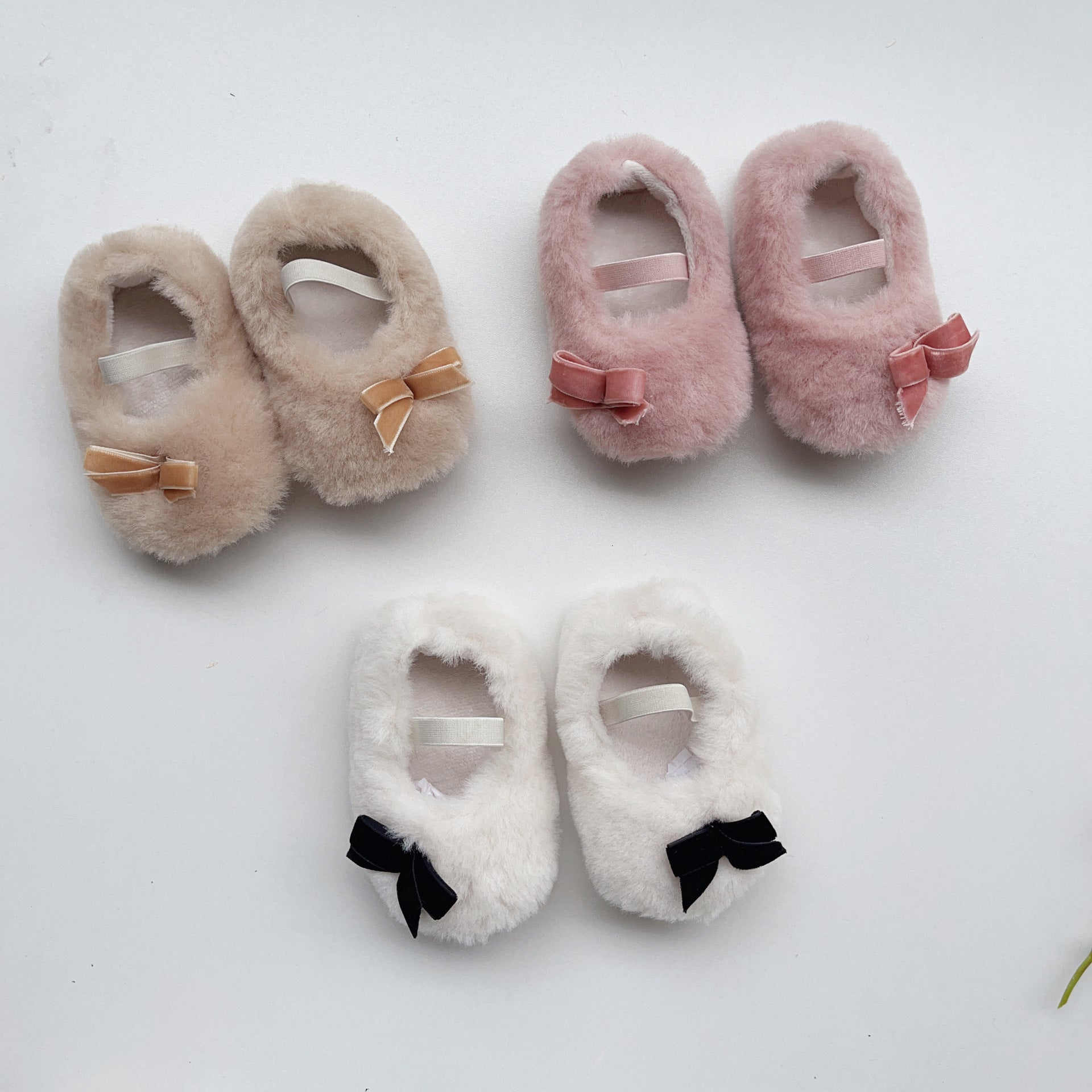 Cute Baby Girl Solid Color Combo Bow Tie Design Plush Warm Anti-Slip shoes in white, pink, and apricot colors, showcasing their soft material and anti-slip sole.