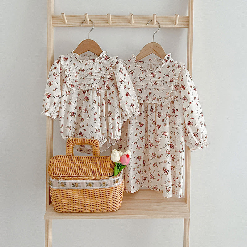 A collection of Ditsy Flower Graphic Sisterly Clothes, featuring floral onesies and dresses in white and red colors, made from soft cotton.