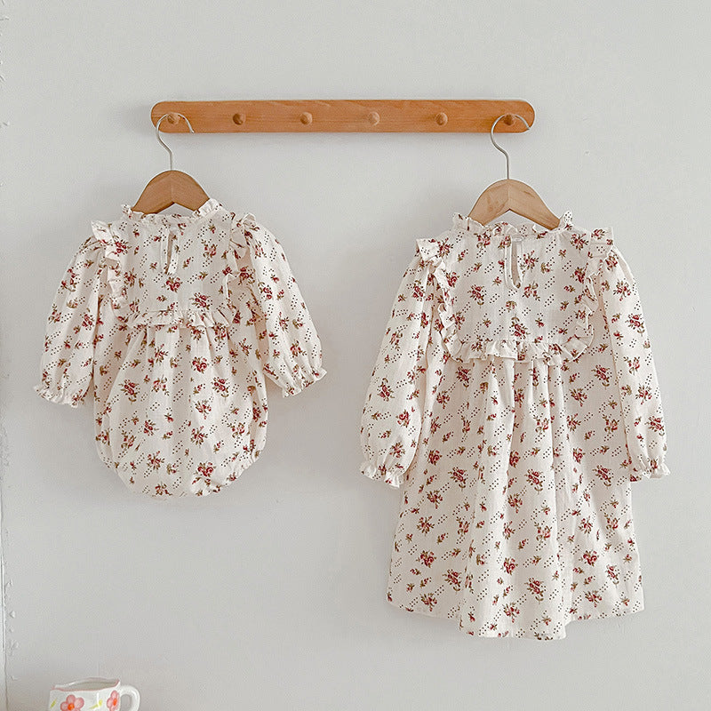 A collection of Ditsy Flower Graphic Sisterly Clothes, featuring floral onesies and dresses in white and red colors, made from soft cotton.