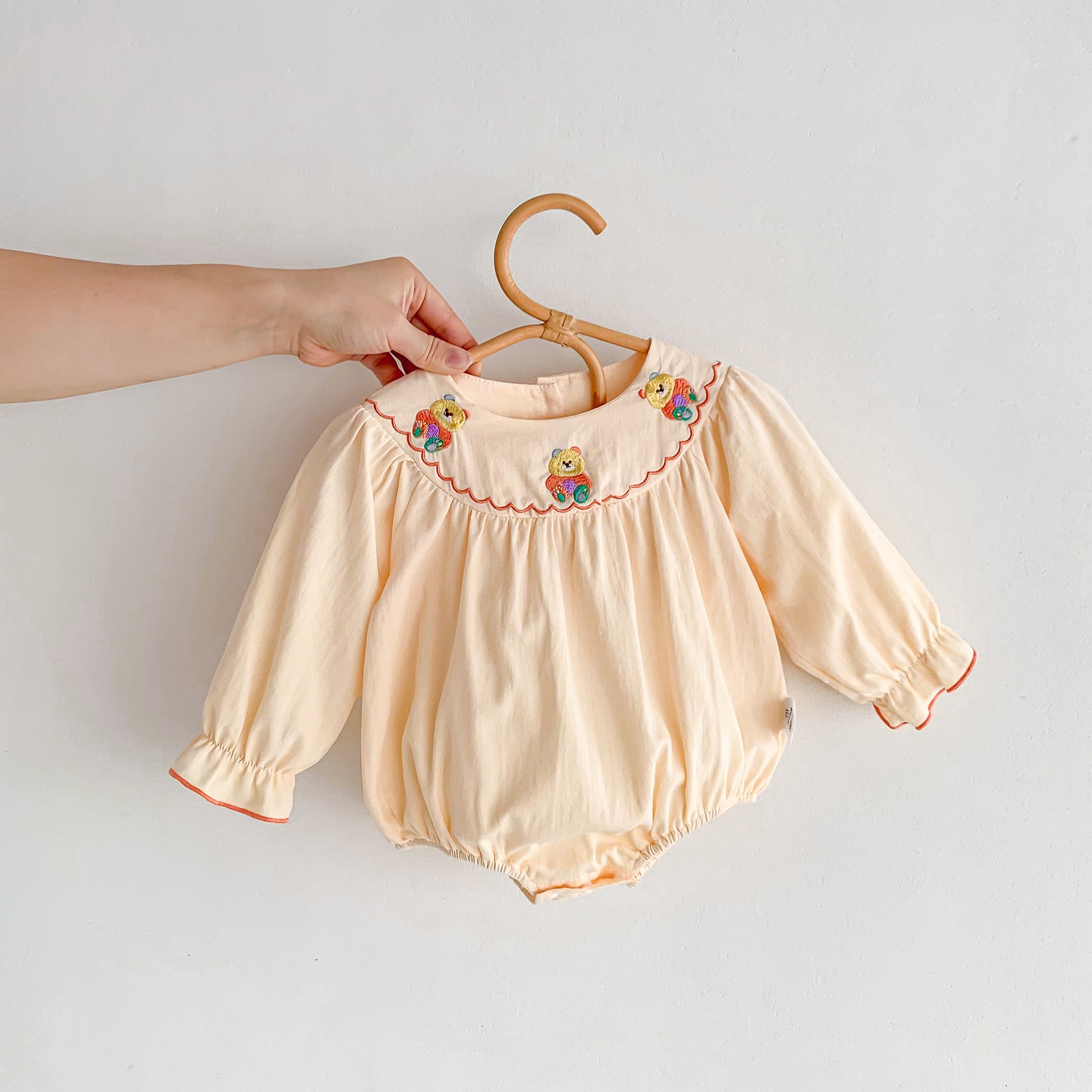 Embroidered design long sleeve apricot onesies for baby girls, featuring floral patterns and soft cotton material.