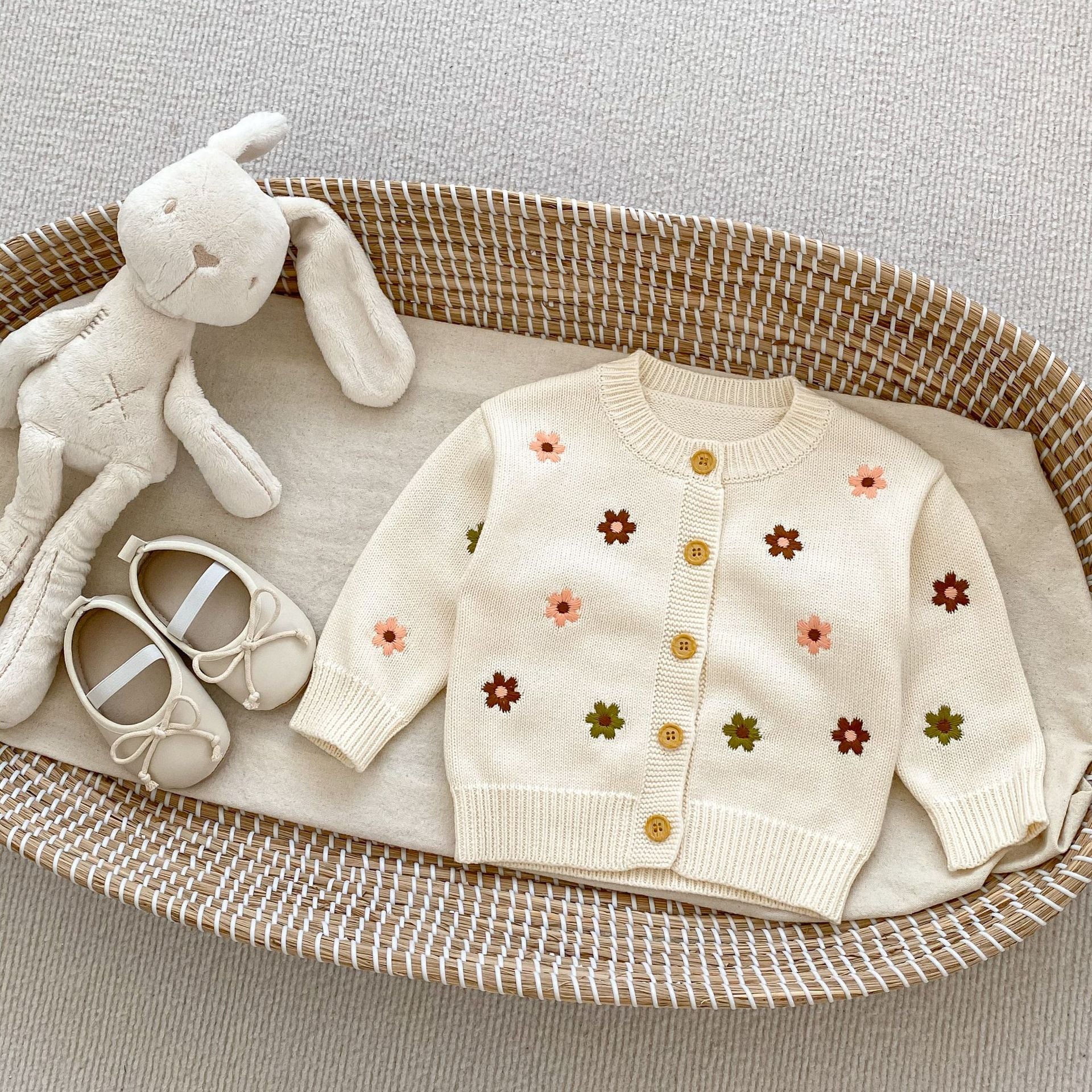 A beige floral graphic knitted cardigan for baby girls, showcasing a soft cotton material and a charming design.