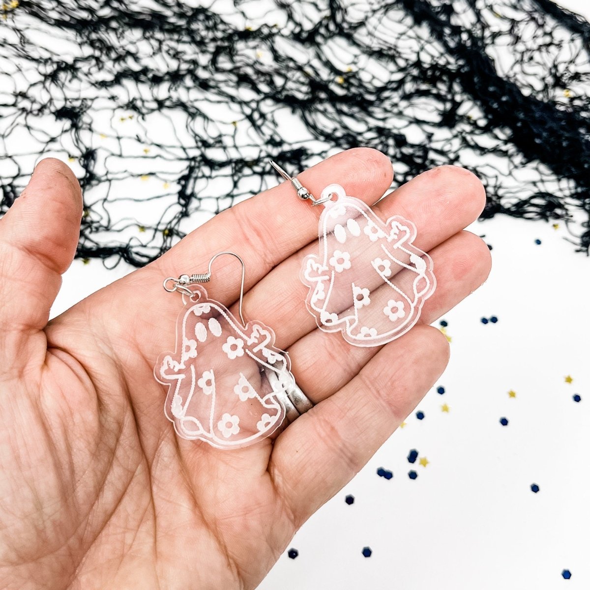 A pair of acrylic ghost dangle earrings featuring a laser-engraved daisy ghost design, perfect for adding a spooky touch to any outfit.