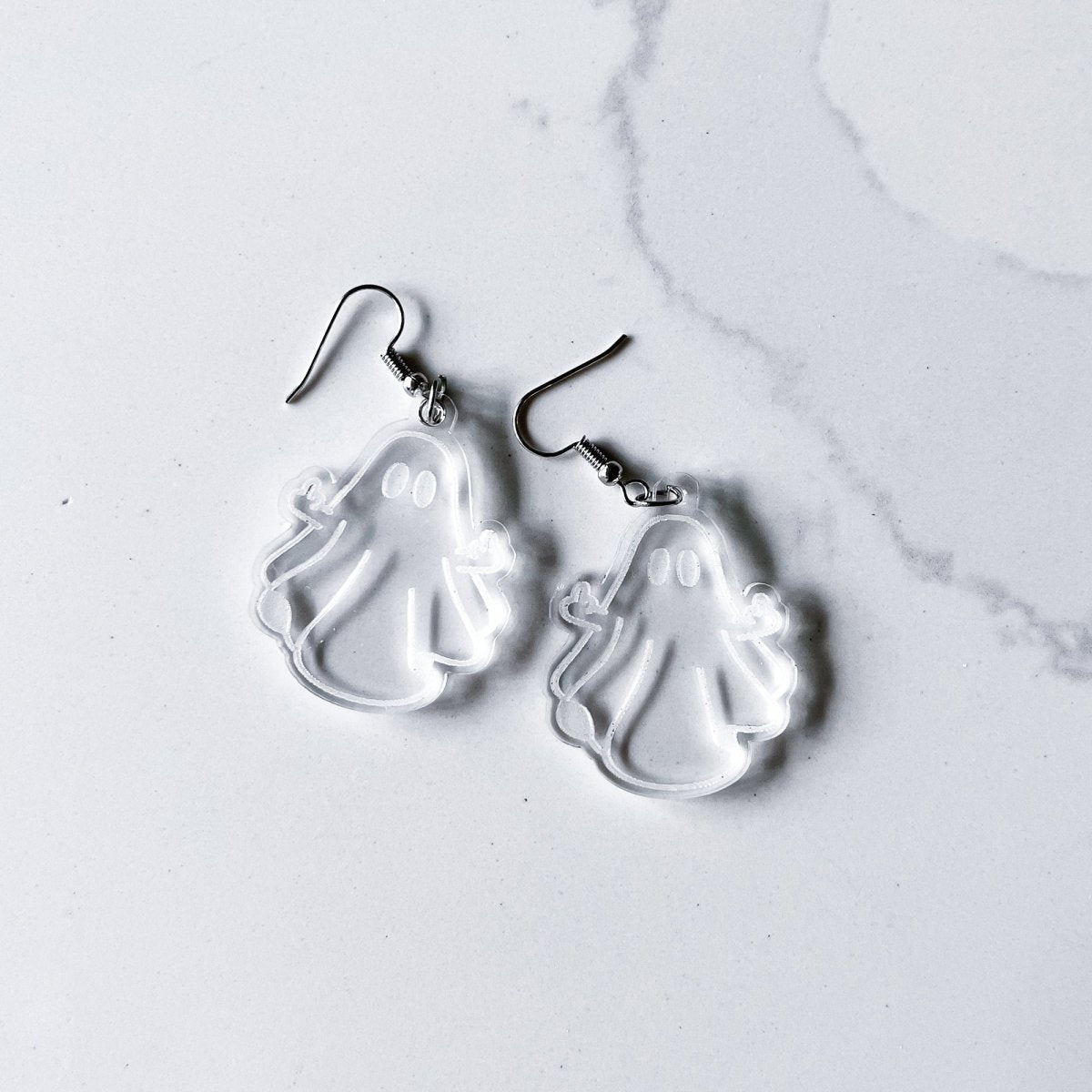 A pair of acrylic ghost dangle earrings featuring a laser-engraved daisy ghost design, perfect for adding a spooky touch to any outfit.