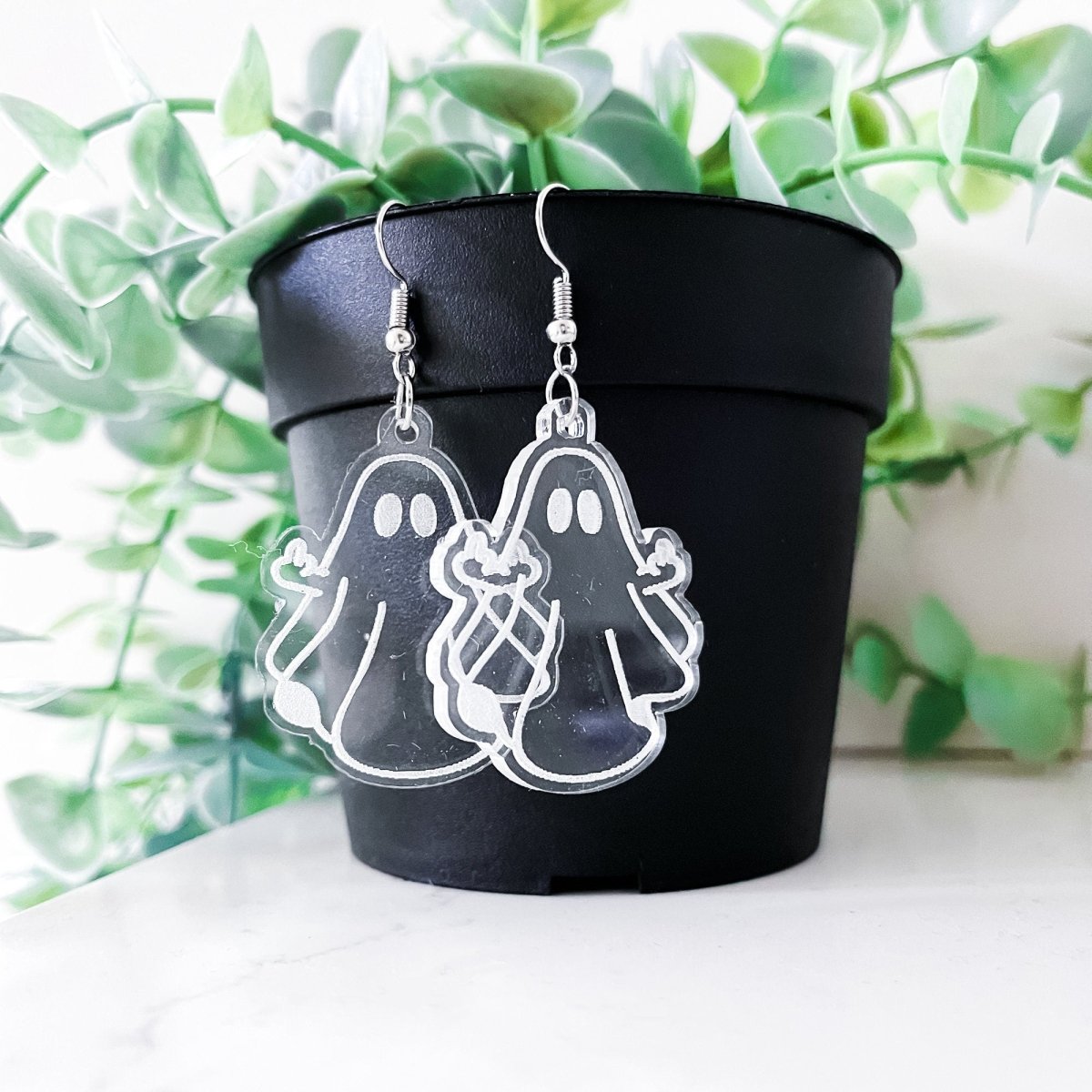 A pair of acrylic ghost dangle earrings featuring a laser-engraved daisy ghost design, perfect for adding a spooky touch to any outfit.