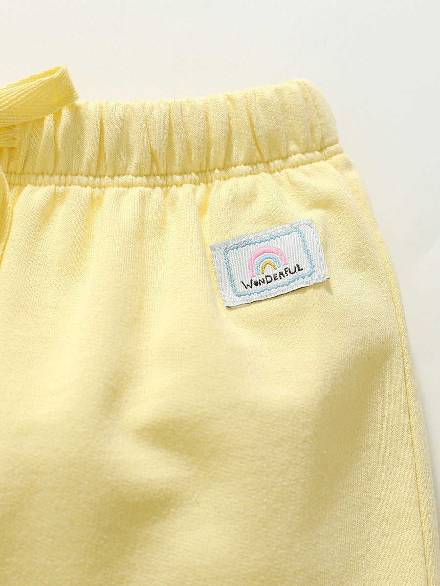 Girls solid color yellow capri pants with rainbow logo, made from soft cotton, perfect for summer wear.