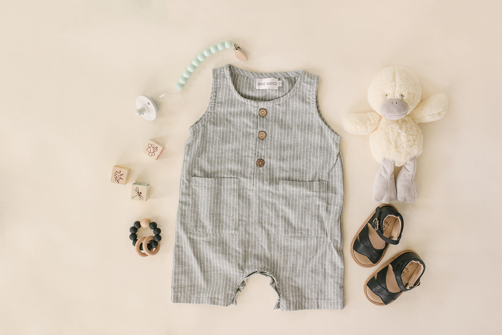 A stylish grey and white striped crop linen romper for babies, featuring diaper snaps and a comfortable fit.