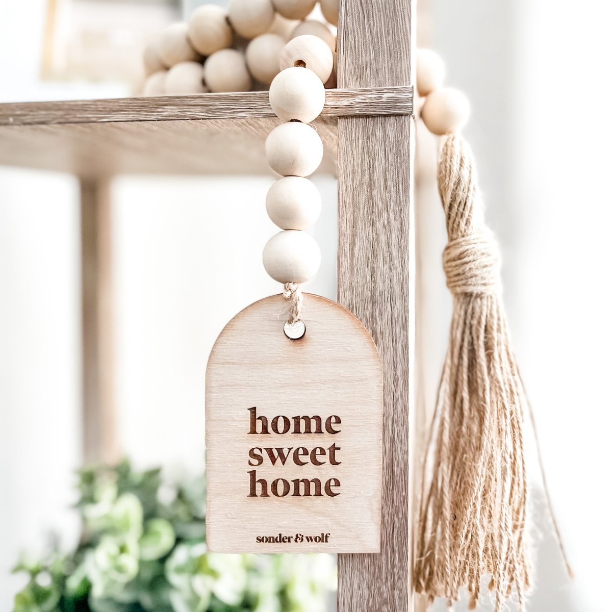 Home Sweet Home Garland featuring natural wood beads and a jute tassel, perfect for home decor.