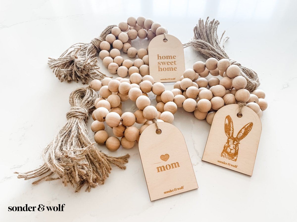 Home Sweet Home Garland featuring natural wood beads and a jute tassel, perfect for home decor.