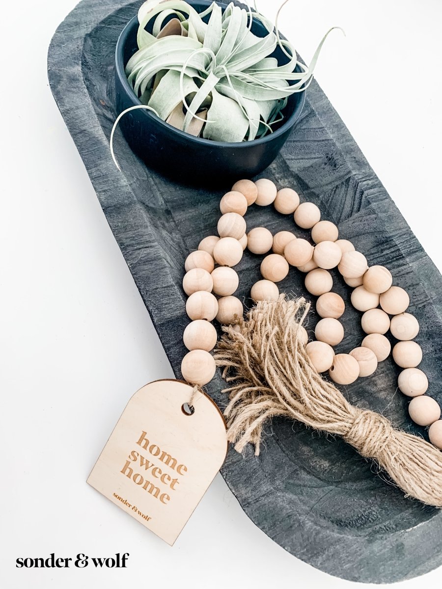 Home Sweet Home Garland featuring natural wood beads and a jute tassel, perfect for home decor.