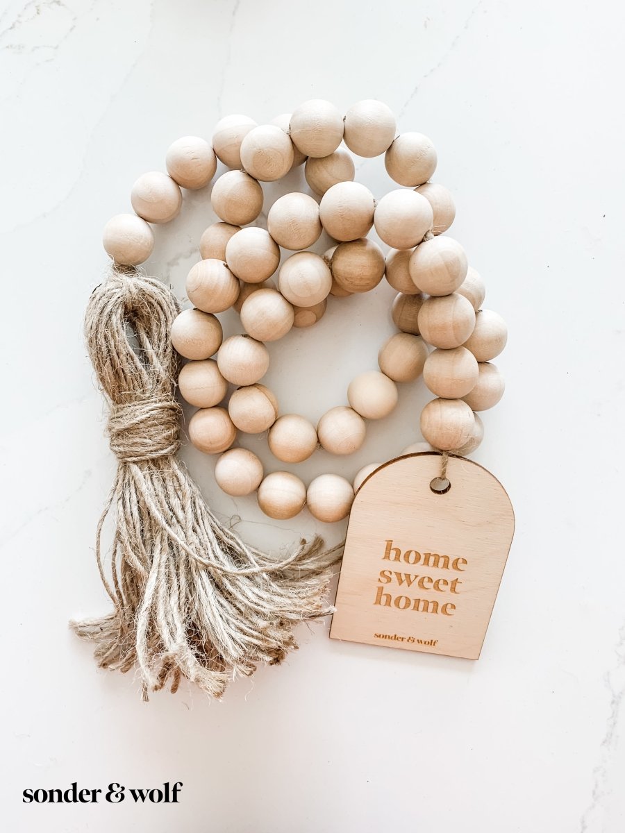 Home Sweet Home Garland featuring natural wood beads and a jute tassel, perfect for home decor.