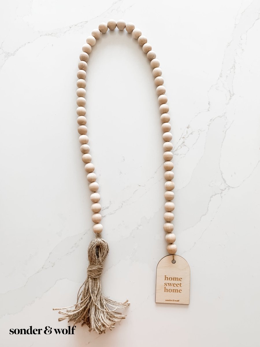 Home Sweet Home Garland featuring natural wood beads and a jute tassel, perfect for home decor.