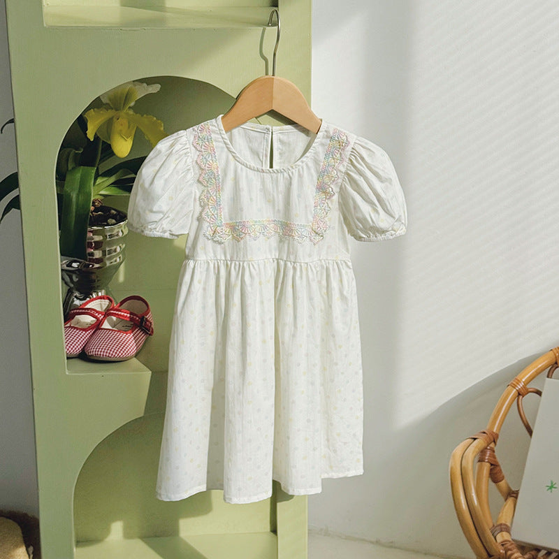 A beige summer dress for girls featuring short sleeves and a playful polka dot pattern, perfect for warm weather outings.