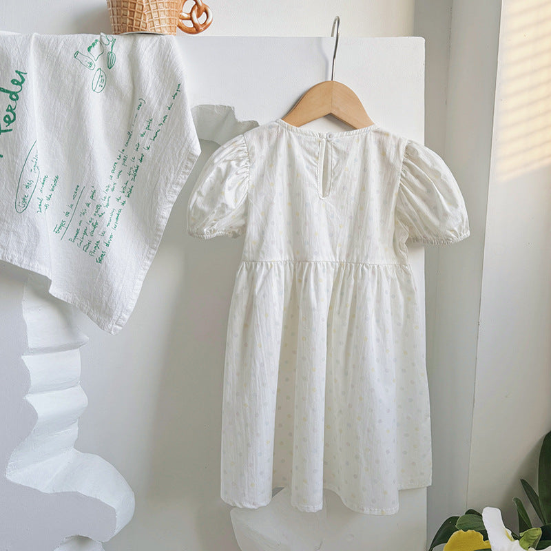 A beige summer dress for girls featuring short sleeves and a playful polka dot pattern, perfect for warm weather outings.