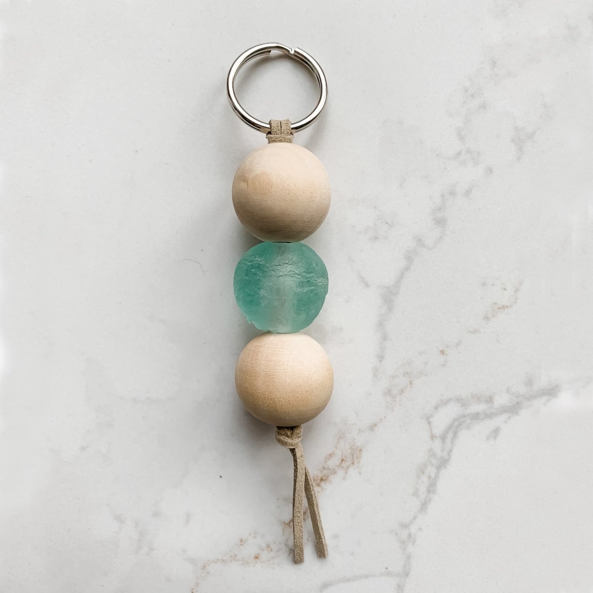 A colorful Sea Glass Bead Keychain featuring recycled glass beads and natural wood beads, attached to a leather string keyring.