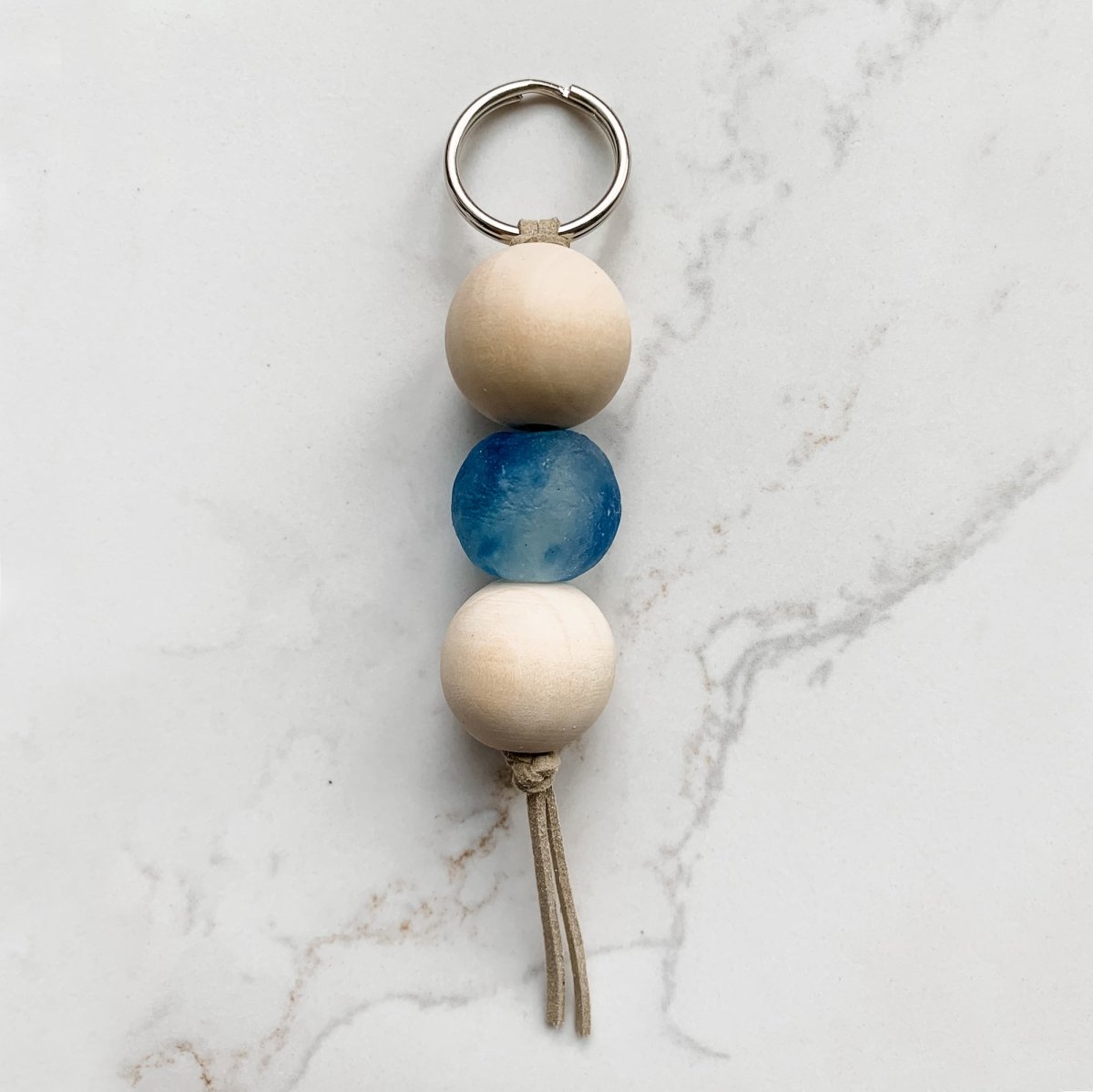 A colorful Sea Glass Bead Keychain featuring recycled glass beads and natural wood beads, attached to a leather string keyring.