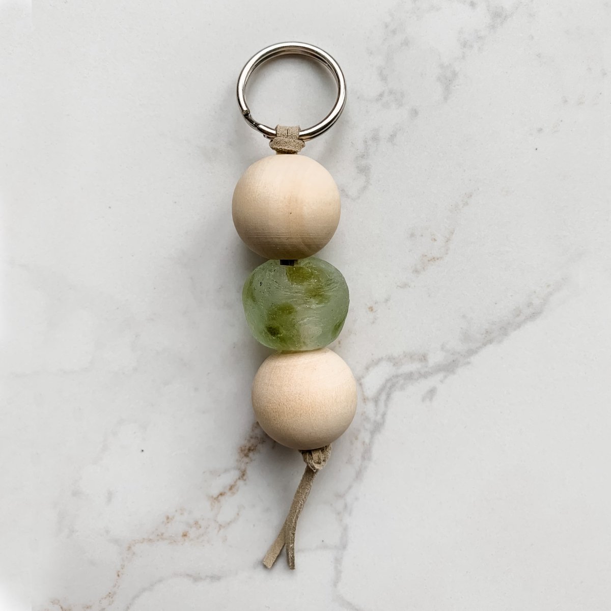 A colorful Sea Glass Bead Keychain featuring recycled glass beads and natural wood beads, attached to a leather string keyring.