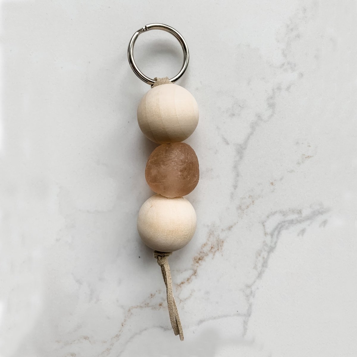 A colorful Sea Glass Bead Keychain featuring recycled glass beads and natural wood beads, attached to a leather string keyring.