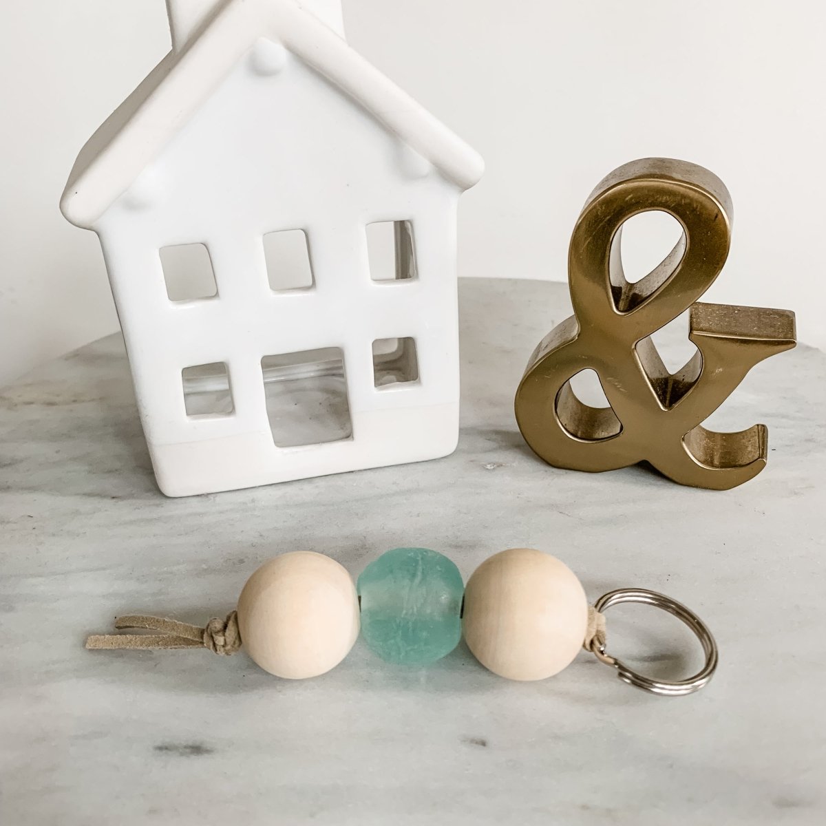 A colorful Sea Glass Bead Keychain featuring recycled glass beads and natural wood beads, attached to a leather string keyring.