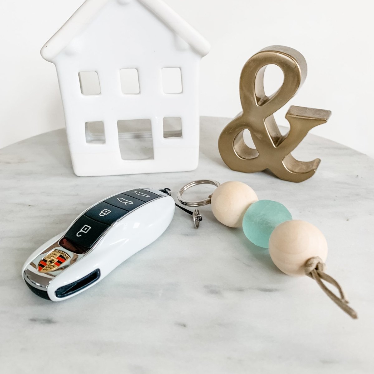 A colorful Sea Glass Bead Keychain featuring recycled glass beads and natural wood beads, attached to a leather string keyring.