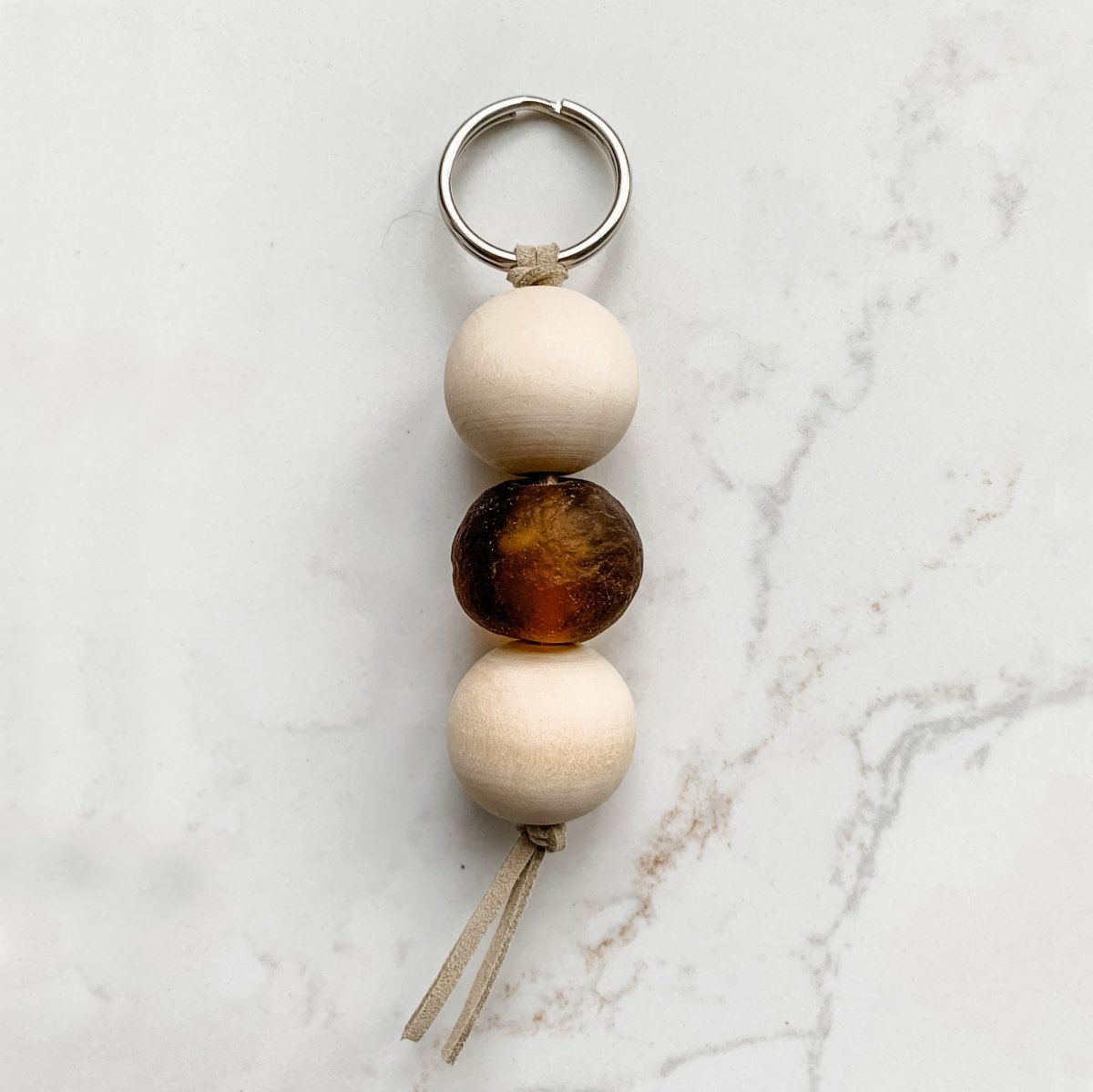 A colorful Sea Glass Bead Keychain featuring recycled glass beads and natural wood beads, attached to a leather string keyring.