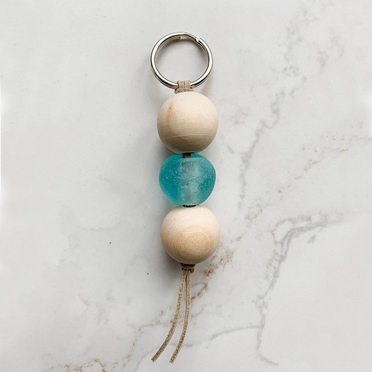 A colorful Sea Glass Bead Keychain featuring recycled glass beads and natural wood beads, attached to a leather string keyring.