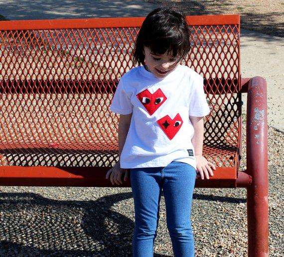 Kids T-shirt featuring I Heart design by Donald Robertson, handmade with felt appliqué on a white fabric.