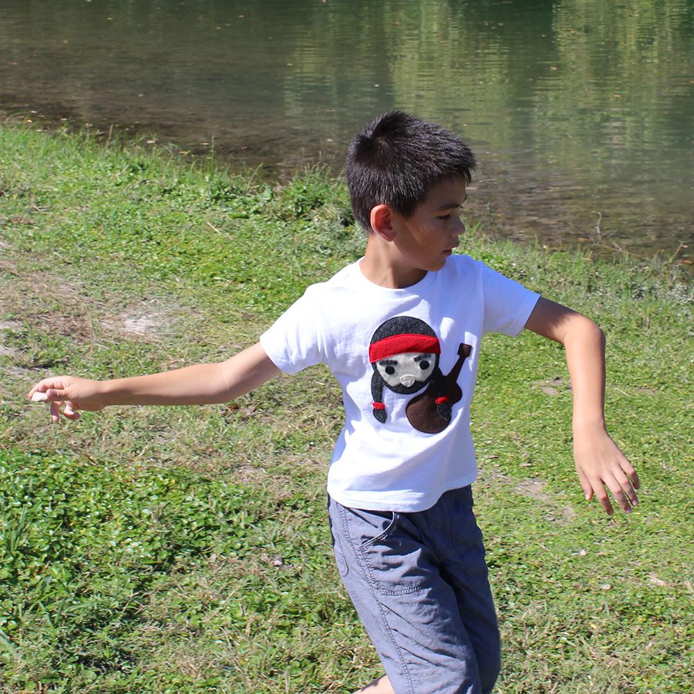 A colorful kids T-shirt featuring Willie the Music Man playing guitar, made with eco-friendly felt appliqué.