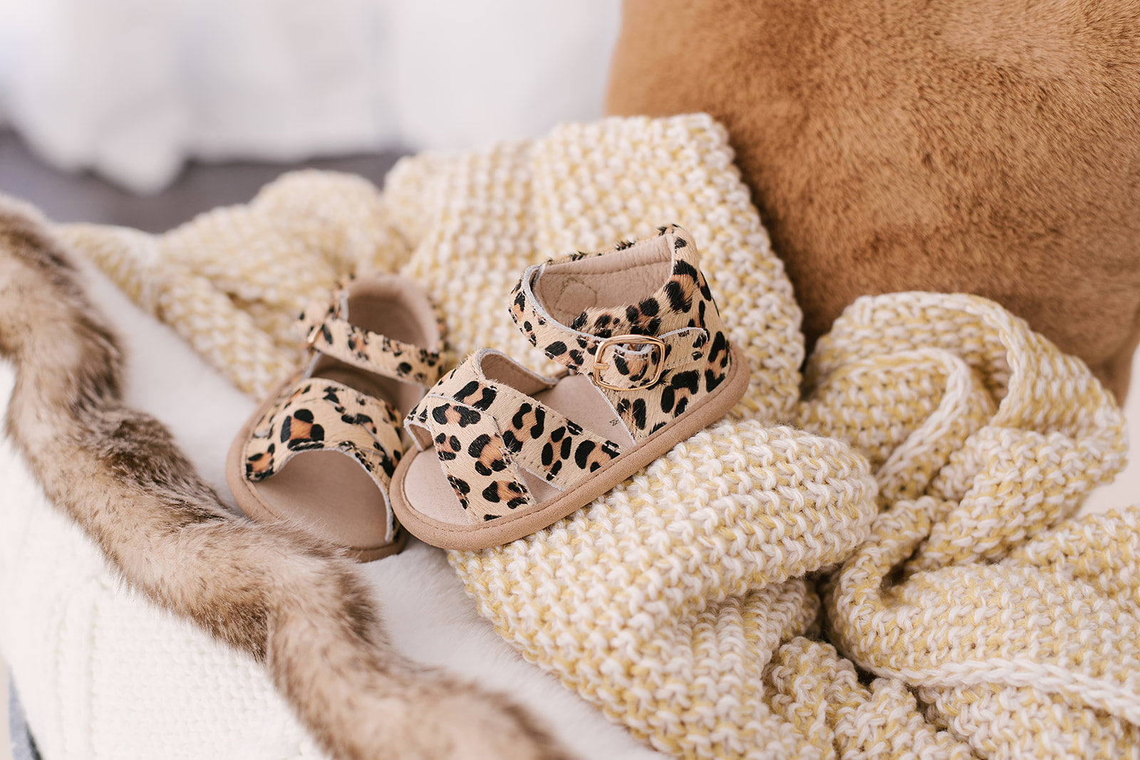 A pair of stylish leopard print baby sandals made of soft leather, featuring rubber treads for safety and comfort.