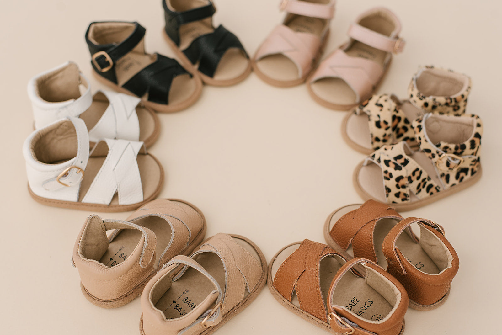 A pair of stylish leopard print baby sandals made of soft leather, featuring rubber treads for safety and comfort.